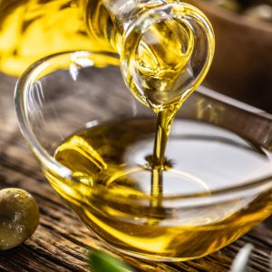 pouring olive oil from carafe to the glass bowl