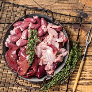 Raw bird giblets meat set, chicken offals, liver, hearts, gizzards Stomach Wooden background Top view Copy space